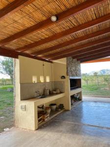 an outdoor kitchen with a sink under a wooden roof at La Pausa. Casa de campo in Deán Funes