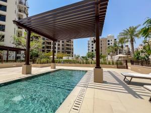 a swimming pool with a wooden pergola over it at Trophy - Burj Al Arad Maison de Reve in Dubai