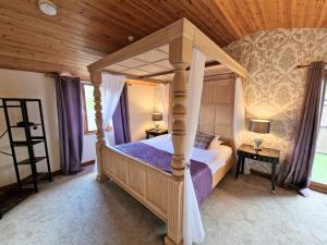 a bedroom with a canopy bed with a wooden ceiling at Lomond 6 with Private Hot Tub - Fife - Loch Leven - Lomond Hills in Kelty +2 photos