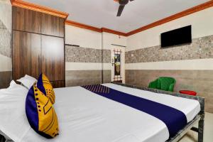 a bedroom with a bed and a tv on the wall at SPOT ON Hotel Maha Lakshmi in Ongole