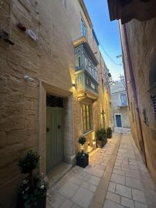 an alley with a green door and a building at Felipe x Casa Norte in Birgu