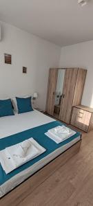 Schlafzimmer mit einem Bett mit blauer Bettwäsche und einem Spiegel in der Unterkunft Apartments Oreha Sveti Vlas in Sweti Wlas