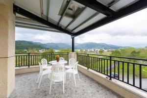 einen Balkon mit einem Tisch, Stühlen und Bergen in der Unterkunft 暖日民宿 in Xingjian