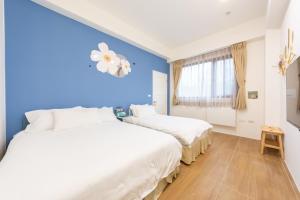 2 Betten in einem Zimmer mit blauen Wänden in der Unterkunft 暖日民宿 in Xingjian