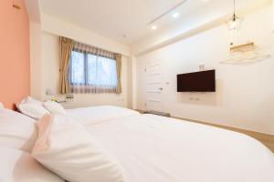 Schlafzimmer mit einem weißen Bett und einem Flachbild-TV in der Unterkunft 暖日民宿 in Xingjian