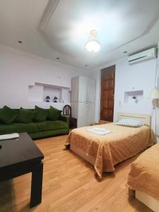 ein Wohnzimmer mit 2 Betten und einem grünen Sofa in der Unterkunft Guest House Lili in Batumi