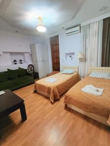 ein Wohnzimmer mit 2 Betten und einem grünen Sofa in der Unterkunft Guest House Lili in Batumi