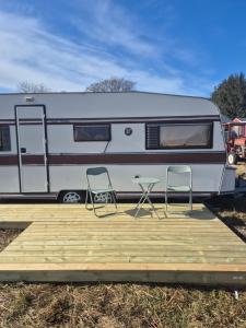 Synes的住宿－Vintage caravan，白色大篷车,配有两把椅子和一张桌子