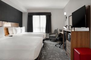 a hotel room with two beds and a flat screen tv at Ramada by Wyndham Cochrane in Cochrane
