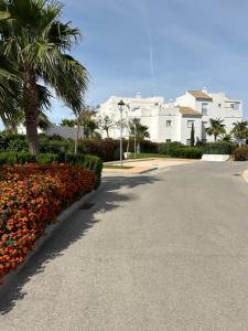 une rue avec des fleurs et des palmiers devant un immeuble dans l'établissement LA CASA DE LOS PATOS Jardines del lago, à Costa de Sanlúcar