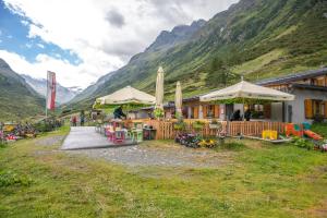a restaurant with tables and umbrellas in front of a mountain at Hotel Garni Bel-Ami in Galtür