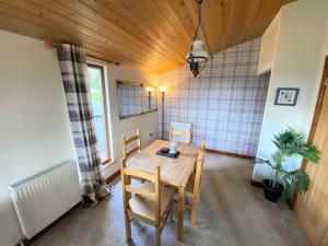 a dining room with a wooden table and chairs at Lomond 6 with Private Hot Tub - Fife - Loch Leven - Lomond Hills in Kelty