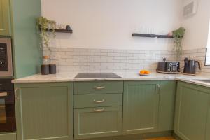 uma cozinha com armários verdes e uma bancada em Wigan Gem: Chic 1BR close to CC em Wigan