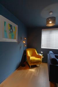 sala de estar con silla amarilla y ventana en Wigan Gem: Chic 1BR close to CC en Wigan