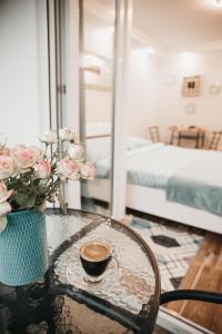 - une table avec une tasse de café et des fleurs dans l'établissement Nefelejcs Apartman Balatonlelle, à Balatonlelle