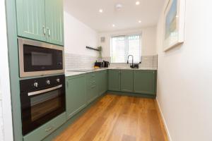 uma cozinha com armários verdes e um fogão forno superior em Wigan Gem: Chic 1BR close to CC em Wigan