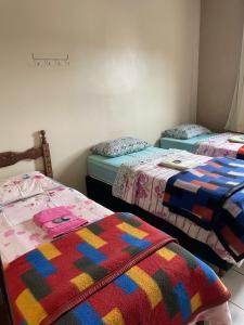 Pousada Zacarias في أورو بريتو: غرفة مع ثلاثة أسرة مع بطانيات ملونة