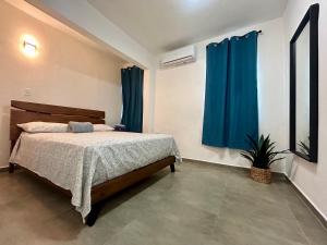 ein Schlafzimmer mit einem Bett mit blauen Vorhängen und einer Pflanze in der Unterkunft Dorado Beach House in Dorado