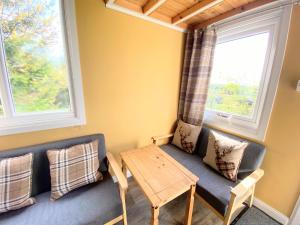 a living room with a couch and a table at Blair Tiny House with Private Hot Tub - Fife - Loch Leven - Lomond Hills in Dunfermline