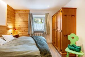 una camera da letto con un letto e una sedia verde di Ciasa Majonade Pozza di Fassa tipo1 a Pozza di Fassa