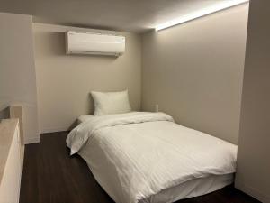 a small bedroom with a bed and a air conditioner at Neighbor's Penthouse 竹屋 in Hiroshima