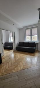 una sala de estar con sofás negros y suelo de madera. en Apartament przy Lipowej en Białystok