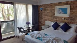 a hotel room with a bed and a balcony at Port Stephens Motel in Nelson Bay