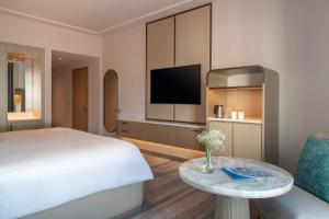 a hotel room with a bed and a tv and a table at Kempinski Hotel Amman in Amman
