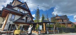 uma mulher em pé em frente a um edifício em Walkowy Dwor em Zakopane