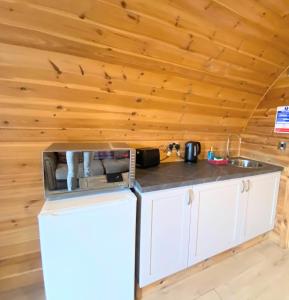 a kitchen with a refrigerator and a sink in a cabin at Pond View Pod 1 with Outdoor Hot Tub - Pet Friendly - Fife - Loch Leven - Lomond Hills in Kelty