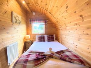 KeltyにあるPond View Pod 1 with Outdoor Hot Tub - Pet Friendly - Fife - Loch Leven - Lomond Hillsの木製の部屋にベッド1台が備わるベッドルーム1室があります。