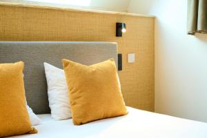 uma cama com almofadas amarelas num quarto em Les Tanneurs em Namur