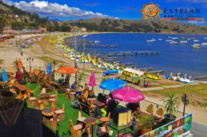a group of people sitting at a beach with umbrellas at HOTEL ESTELAR del TITICACA in Copacabana