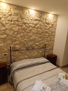 Bett in einem Zimmer mit einer Steinmauer in der Unterkunft Il Casale Di Ginetto in Cascia