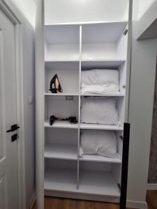 ピテシュティにあるSweet homeの白い棚と靴が備わるウォークインクローゼット