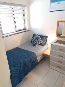 a small bedroom with a bed and a desk with a laptop at 78 Cabanas Del Mar in Kingsburgh