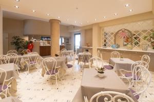 a restaurant with white tables and white chairs at Hotel San Francisco in Viareggio