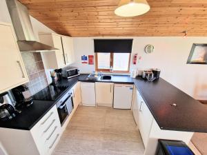 a kitchen with black counter tops and white cabinets at Torridon 12 with Private Hot Tub - Fife - Loch Leven - Lomond Hills in Kelty