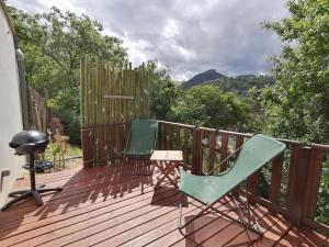 a deck with two chairs and a grill on it at Le cocon Cévenol in Anduze
