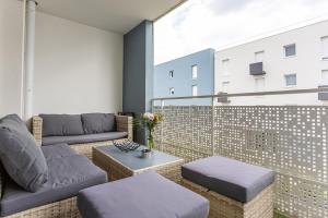 einen Balkon mit Sofas, einem Tisch und einem Gebäude in der Unterkunft Le cocon familial in Séné