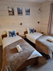 dwa łóżka w pokoju z obrazami na ścianie w obiekcie Schronienie Orłów Domek Zawoja w Zawoi