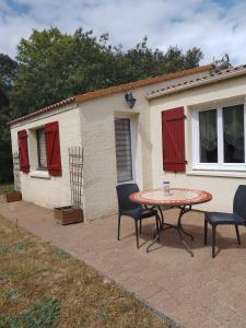 een patio met een tafel en stoelen voor een huis bij Chambre sous les mimosas 2kms plage in Saint-Jean-de-Monts
