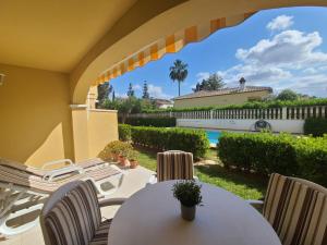 een terras met een tafel en stoelen en een zwembad bij Bungalow Aldea del Mar in Els Poblets