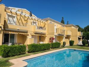 uma villa com piscina em frente a um edifício em Bungalow Aldea del Mar em Els Poblets