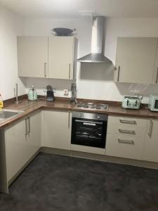 a kitchen with white cabinets and a stove top oven at Luna Church Conversion 1 in Blackpool