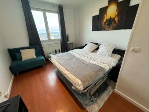 een slaapkamer met een bed en een stoel erin bij Logement calme et cosy au Centre-Ville in Saint-Cyr-lʼÉcole