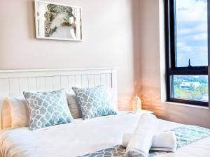 1 cama con almohadas azules y blancas y ventana en Holiday Style 2 BRStudy Apartment in Olympic Park, en Sídney