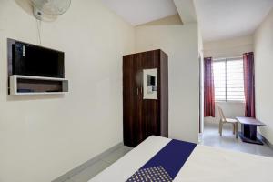a bedroom with a bed and a tv on a wall at SPOT ON Capital Inn Hotel Rooms in Gundlupet