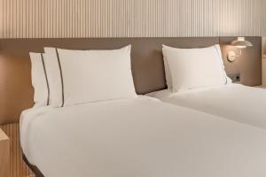 ローマにあるホテル クローディオのホテルルーム内のベッド2台(白い枕付)