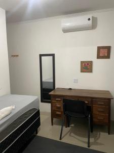 1 dormitorio con escritorio, 1 cama y espejo en Pousada Aeroporto Viracopos Campinas, en Viracopos